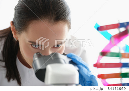 Woman scientist looking through a microscope, studying dna Woman scientist looking through a microscope, studying dna 84151069