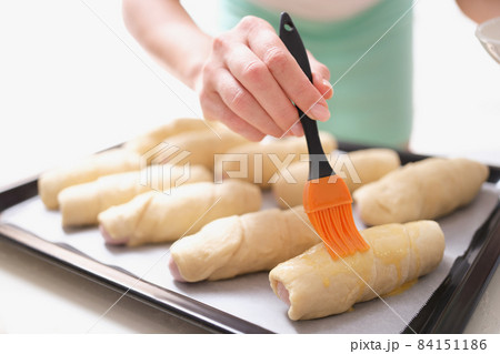 A woman before baking with a brush lubricates dough products A woman before baking with a brush lubricates dough products 84151186
