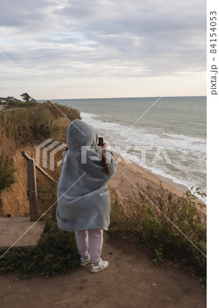 Young woman on cold autumn seashore posing at camera Young woman on cold autumn seashore posing at camera 84154053