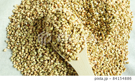 Buckwheat scattered background, raw green cereal in a wooden spoon. Healthy groats. Organic raw non-fried vegetarian food. The concept of a healthy and balanced diet. Diet product. healthy groats. Buckwheat scattered background, raw green cereal in a wooden spoon. Healthy groats. Organic raw non-fried vegetarian food. The concept of a healthy and balanced diet. Diet product. healthy groats. 84154886