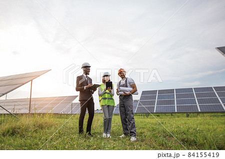 Indian technician standing at solar farm with two inspectors Indian technician standing at solar farm with two inspectors 84155419