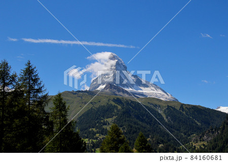 上空の筋雲が印象的なマッターホルン　緑の山麓と木々も映える 84160681