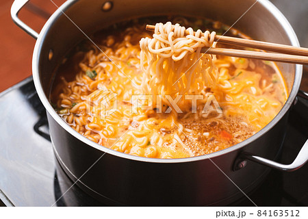 Asian spicy instant noodles soup cooking in hot pot with chopsticks 84163512