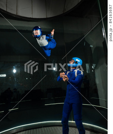 A man teaches a boy to fly in a wind tunnel. A man teaches a boy to fly in a wind tunnel. 84163697