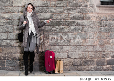 girl in hood and coat with baggage near wall girl in hood and coat with baggage near wall 84164935