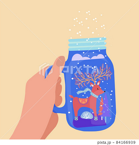 hand holding mason jar with winter landscape and deer 84166939