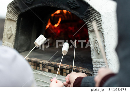 Friends roast marshmallows in a Pompeian oven in the backyard. Front view. 84168473