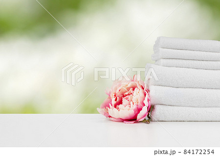 Towels with flowers on light table against blurred background 84172254