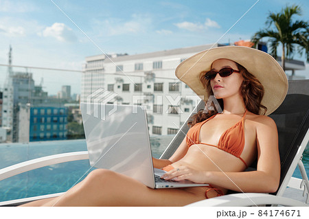Woman Working on Laptop by Pool Woman Working on Laptop by Pool 84174671