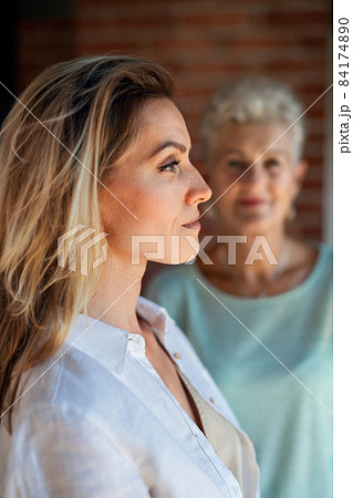 Senior mother looking at her adult daughter indoors at home. Selective focus on woman in foreground. Senior mother looking at her adult daughter indoors at home. Selective focus on woman in foreground. 84174890