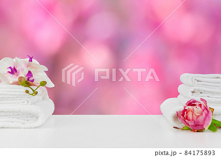 Towels with flowers on light table against blurred background 84175893