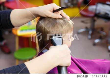 Children's hairdresser. A minor boy getting a haircut at a children's hairdresser. 84176115