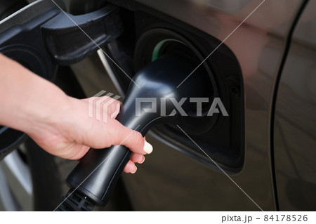 Woman put fuel nozzle on petrol station to refuel automobile with diesel 84178526