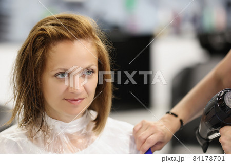 Client woman after refreshing haircut looking in mirror on herself Client woman after refreshing haircut looking in mirror on herself 84178701