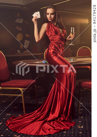 Young charming female is posing at a poker table in vip casino. Young charming female is posing at a poker table in vip casino. 84179428