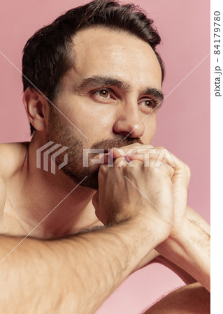 Close-up portrait of young handsome bearded shirtless man isolated on pink studio background. Natural beauty Close-up portrait of young handsome bearded shirtless man isolated on pink studio background. Natural beauty 84179780