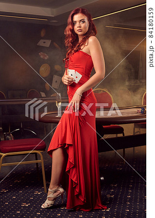 Charnimg sexy woman is posing against a poker table in luxury casino. 84180159