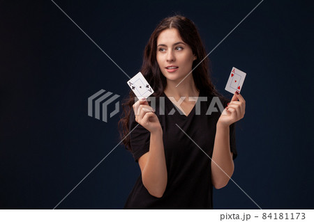 Curly hair brunette is posing with playing cards in her hands. Poker concept on a black background. Casino. 84181173