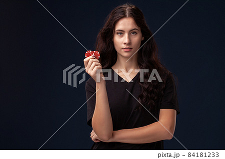 Curly hair brunette is posing with red gambling chips in her hands. Poker concept on a black background. Casino. Curly hair brunette is posing with red gambling chips in her hands. Poker concept on a black background. Casino. 84181233