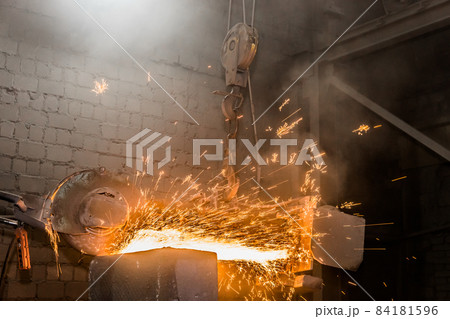 Heavy grinding equipment suspended on a chain with a hook processes and cleans cast iron reinforced concrete tubing in the workshop of an industrial plant Heavy grinding equipment suspended on a chain with a hook processes and cleans cast iron reinforced concrete tubing in the workshop of an industrial plant 84181596