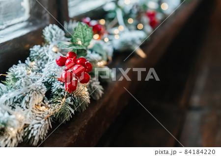 Christmas garland with red berries and snow on the tree, on the window. Christmas garland with red berries and snow on the tree, on the window. 84184220