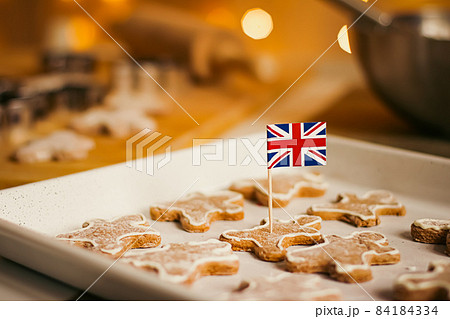 British holiday and Christmas baking concept. Union Jack flag of Great Britain and gingerbread men biscuits in the kitchen in England British holiday and Christmas baking concept. Union Jack flag of Great Britain and gingerbread men biscuits in the kitchen in England 84184334