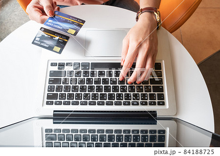 Top view of someone hand holding credit card during using laptop for online shopping. Online shopping is the process of buying goods and services from merchants over the Internet. Top view of someone hand holding credit card during using laptop for online shopping. Online shopping is the process of buying goods and services from merchants over the Internet. 84188725