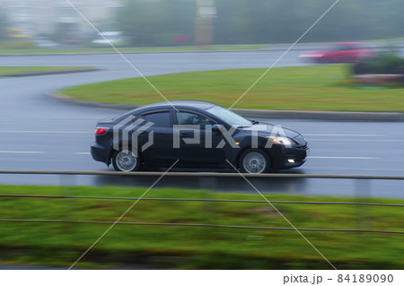 Car drives on city street on wet asphalt at foggy summer day Car drives on city street on wet asphalt at foggy summer day 84189090