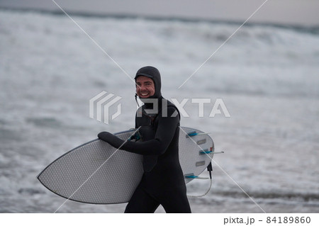 Arctic surfer going by beach after surfing 84189860