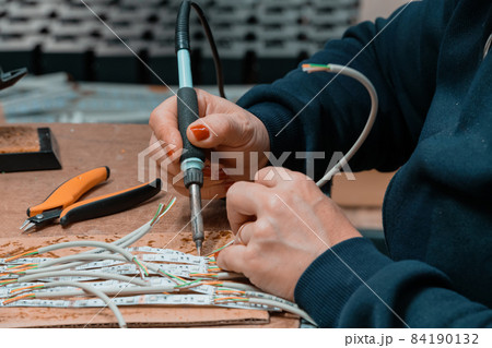 Industrial worker woman soldering cables of manufacturing equipment in a factory 84190132