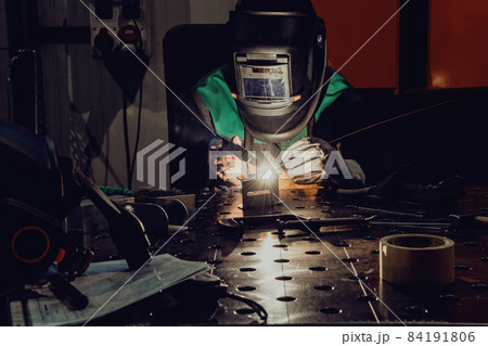 A woman employed in a modern factory for the production and processing of metals in a work uniform welding metal materials 84191806
