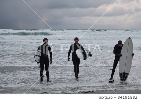 Arctic surfers going by beach after surfing Arctic surfers going by beach after surfing 84191882