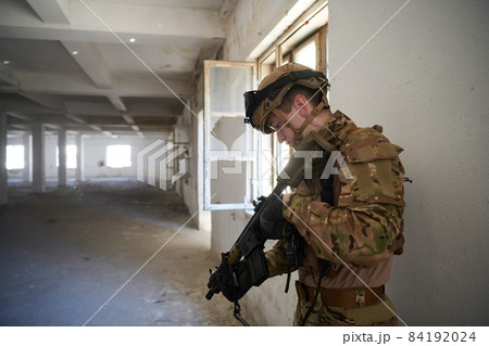 soldier in action near window changing magazine and take cover 84192024