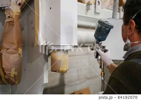 A worker painting to mechanical part with airless spray 84192070