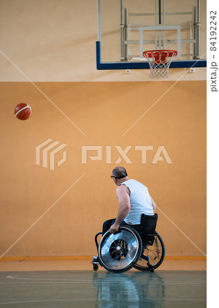 a war invalid in a wheelchair trains with a ball at a basketball club in training with professional sports equipment for the disabled. the concept of sport for people with disabilities 84192242