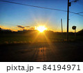 日没の輝く太陽と電柱のある田舎の夕暮れの街並みの風景 84194971