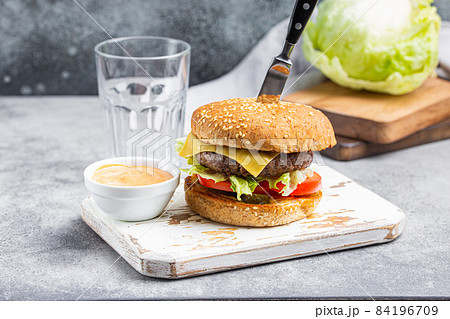 Delicious burger pierced with knife with sauce and empty glass Delicious burger pierced with knife with sauce and empty glass 84196709