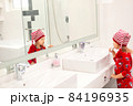 little girl in santa claus hat and red pajama brushing teeth in white bathroom in the morning on Christmas holidays 84196935