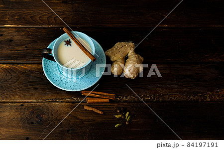 Indian tea masala chai. Seasoned chai masala tea with milk and spices on a dark wooden background. 84197191