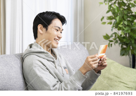 リビングで預金通帳を見て喜ぶ男性 84197693