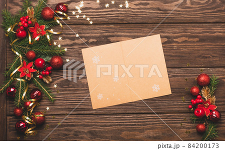 Festive background red Christmas balls toys green branches spruce serpentine sparkles clean blank sheet for text wooden dark background Festive background red Christmas balls toys green branches spruce serpentine sparkles clean blank sheet for text wooden dark background 84200173