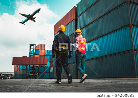 Industrial worker works with co-worker at overseas shipping container port 84200635