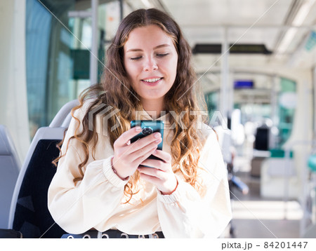 Portrait of a positive girl on public transport and texting on a mobile phone 84201447