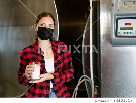 Woman with milk glass at milking parlor Woman with milk glass at milking parlor 84201517