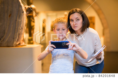 Boy using phone while in museum 84201648