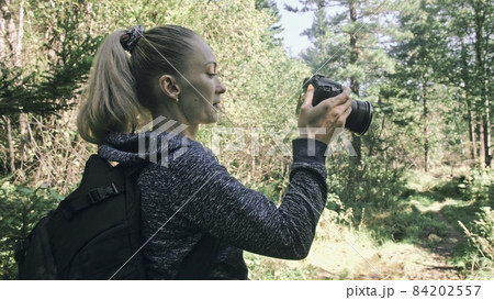 Traveler photographing scenic view in forest. One caucasian woman shooting nice magic look. Girl take photo video on dslr mirrorless camera. Traveler photographing scenic view in forest. One caucasian woman shooting nice magic look. Girl take photo video on dslr mirrorless camera. 84202557