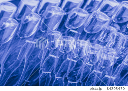 Glass medical ampoule vial for injection. Medicine is liquid sodium chloride with of aqueous solution in ampulla. Close up. Bottles ampule multicolor. Glass medical ampoule vial for injection. Medicine is liquid sodium chloride with of aqueous solution in ampulla. Close up. Bottles ampule multicolor. 84203470