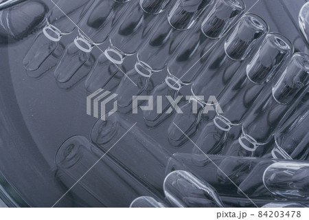 Glass medical ampoule vial for injection. Medicine is liquid sodium chloride with of aqueous solution in ampulla. Close up. Bottles ampule multicolor. Glass medical ampoule vial for injection. Medicine is liquid sodium chloride with of aqueous solution in ampulla. Close up. Bottles ampule multicolor. 84203478