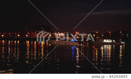 Luxurious modern private yacht and boat at the pier at night. Colorful lights of city glow shine reflected in water wave at nighttime. Luxurious modern private yacht and boat at the pier at night. Colorful lights of city glow shine reflected in water wave at nighttime. 84203695