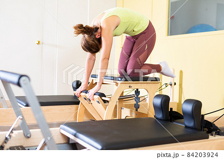 Young woman doing stretching exercises on pilates combo chair 84203924